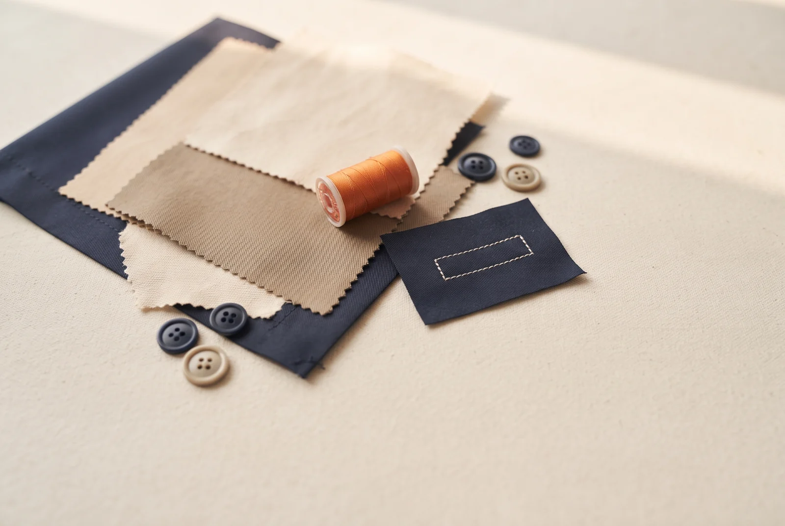 Navy and stone workwear fabric swatches with thread and buttons